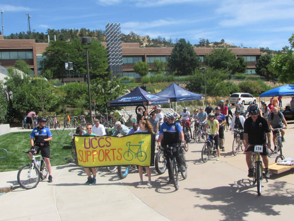 people holding a banner that reads "uccs supports bicycles"