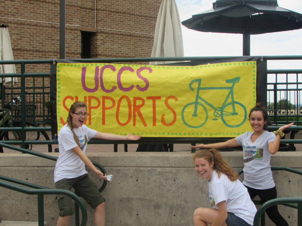 cyclists with a banner that reads "uccs supports bicycles"